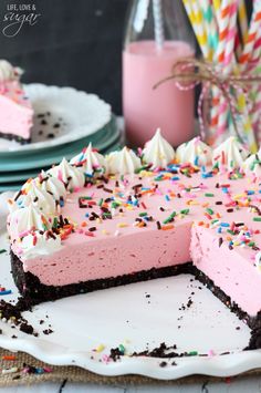 a cake with pink frosting and sprinkles sitting on top of a table