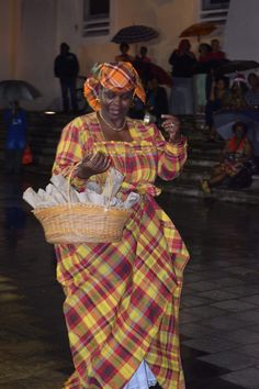 a woman dressed in plaid is walking with an umbrella and holding a basket full of food