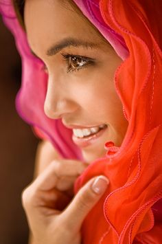 a close up of a person wearing a red head scarf and smiling at the camera