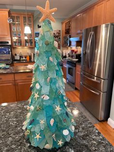 a christmas tree made out of sea glass and starfish on a granite counter top