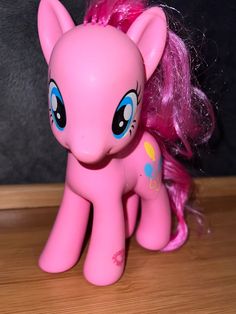 a pink pony with blue eyes sitting on top of a wooden table