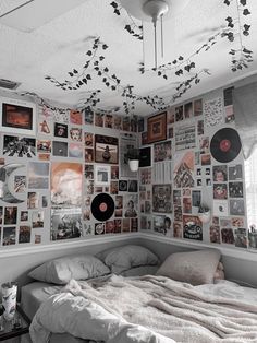 a bed with lots of pictures on the wall above it and a record player hanging from the ceiling