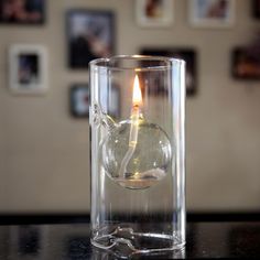 a single candle in a glass vase on a table