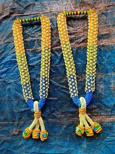 two necklaces with beads and chains on a blue cloth covered surface, one is yellow and the other is green