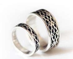 two silver rings with intricate designs on them sitting side by side against a white background