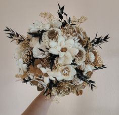 a bridal bouquet in someones hand with flowers and leaves on the bottom half