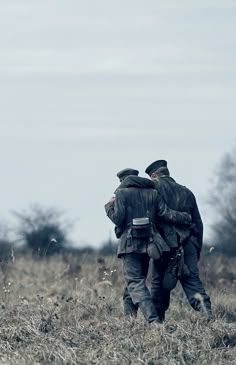 two men walking through a field with one holding the other's arm around his neck