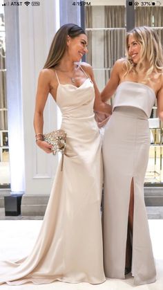 two beautiful women standing next to each other in formal wear and one is holding the hand of another woman