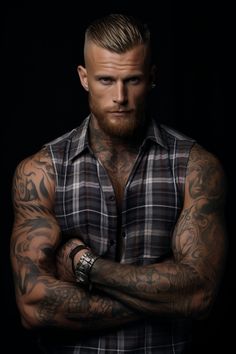 a man with tattoos on his arms and chest is posing for a photo in front of a black background