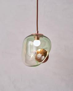 a glass light hanging from a ceiling fixture with a brown cord attached to the end