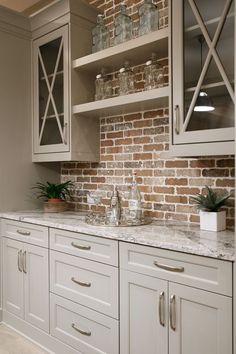 a kitchen with white cabinets and brick wall