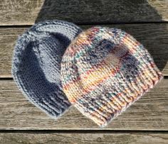 two knitted hats sitting on top of a wooden table next to each other,