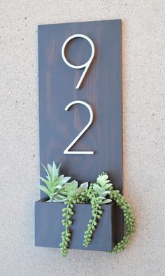 a house number sign with succulents on it