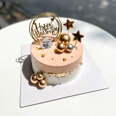 a birthday cake sitting on top of a white table with gold stars and decorations around it