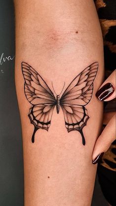 a woman's leg with a tattoo of a butterfly on the side, and black ink