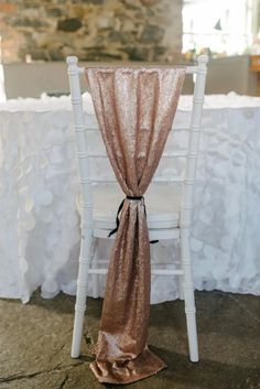 a chair with a gold sash on top of it next to a white table cloth