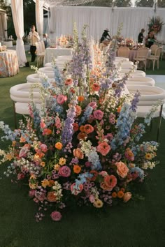 an arrangement of flowers is on the ground at a wedding reception with white linens