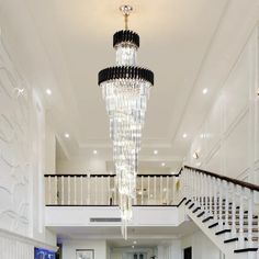 a chandelier hanging from the ceiling in a living room with white walls and stairs