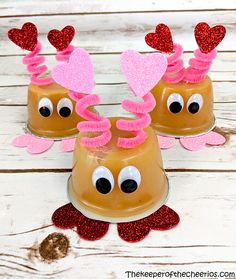 three cups with hearts and antlers on them sitting on top of a wooden table