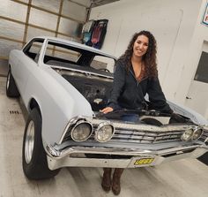 a woman standing next to a car in a garage