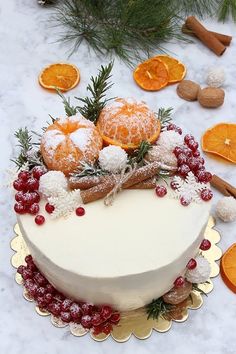 a white cake with oranges and cranberries sitting on top of a table