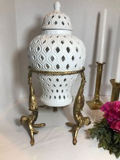 a white vase sitting on top of a table next to two candles and a pink flower