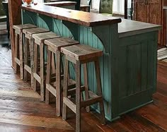 a kitchen with an island and stools in the center, surrounded by wood flooring