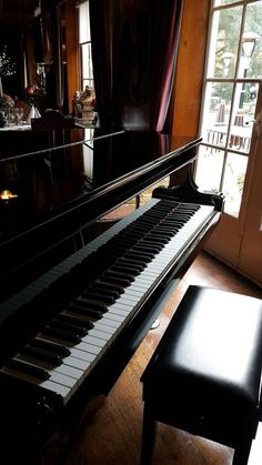 a piano sitting in front of a window next to a bench