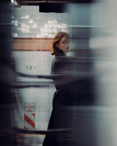 a woman standing in front of a tiled wall