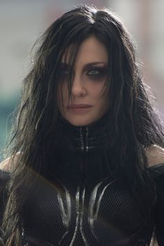 a close up of a person with long hair and black makeup wearing a costume that has spider - man on it's chest