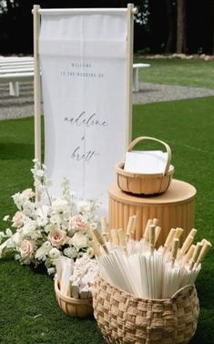 an outdoor ceremony set up with umbrellas and flowers on the grass in front of a welcome sign