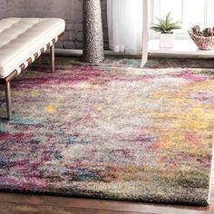 an area rug with multicolored designs and a bench in the corner next to it