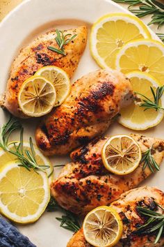 grilled chicken with lemons and rosemary garnish on a white platter