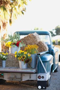 an old truck with flowers and hay in the back