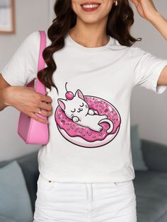 Indulge in the playfulness of our Kitten on a Donut Float Tee, a whimsical addition to any wardrobe! This unisex shirt features an irresistibly cute cat peacefully adorning a sprinkle-dotted pink donut, striking the perfect balance between adorable and stylish. Ideal for cat enthusiasts of all ages, it serves as a delightful conversation starter or a thoughtful gift. The versatile graphic design blends seamlessly with various outfits, ensuring you stand out in any casual setting. Crafted for com White Kawaii T-shirt With Cat Print, Playful Cat Design Crew Neck T-shirt, Playful Crew Neck T-shirt With Cat Design, Playful Cotton T-shirt With Cat Design, Playful Cotton T-shirt With Cat Print, Playful Cotton Cat Print T-shirt, Playful Short Sleeve T-shirt With Cat Design, Pink Kawaii T-shirt With Cat Design, Donut Float