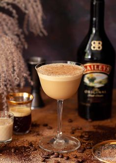 a drink sitting on top of a wooden table next to two glasses filled with liquid