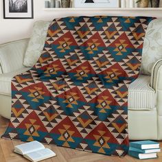 a couch with a blanket on top of it in front of a book shelf and books