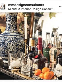 an assortment of liquor bottles and glasses on a table with a vase in the background