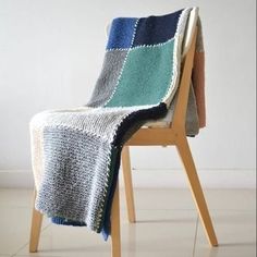 a chair with a blanket on top of it in front of a white wall and floor