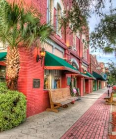 a red brick building with green awnings and palm trees on the side walk