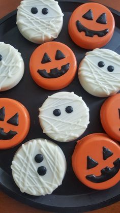 halloween cookies decorated with icing and jack - o'- lantern faces on a black plate