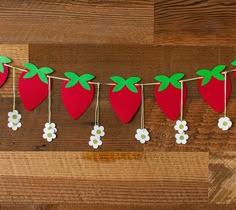 paper strawberries and daisies are hanging on a line with pegs for decoration