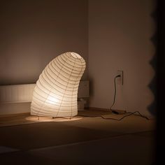 a white lamp sitting on top of a hard wood floor next to a phone charger