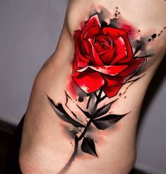 a red rose tattoo on the side of a woman's stomach, with black ink splots