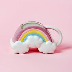 a white and pink toy with a rainbow in the middle on a pink background,