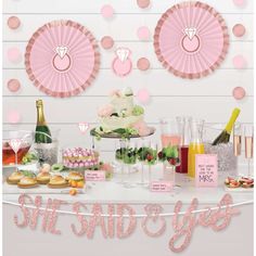 a table topped with lots of desserts and drinks next to a wall covered in pink polka dots