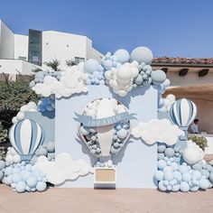 a large balloon arch in front of a building with blue and white balloons on it