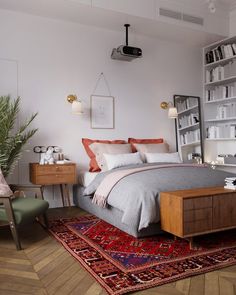 a bedroom with a bed, chair and rug on the floor in front of a bookshelf