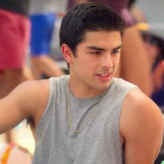 a young man wearing a gray tank top holding a cell phone