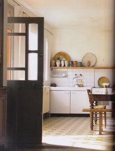 an open door leading to a kitchen with white appliances